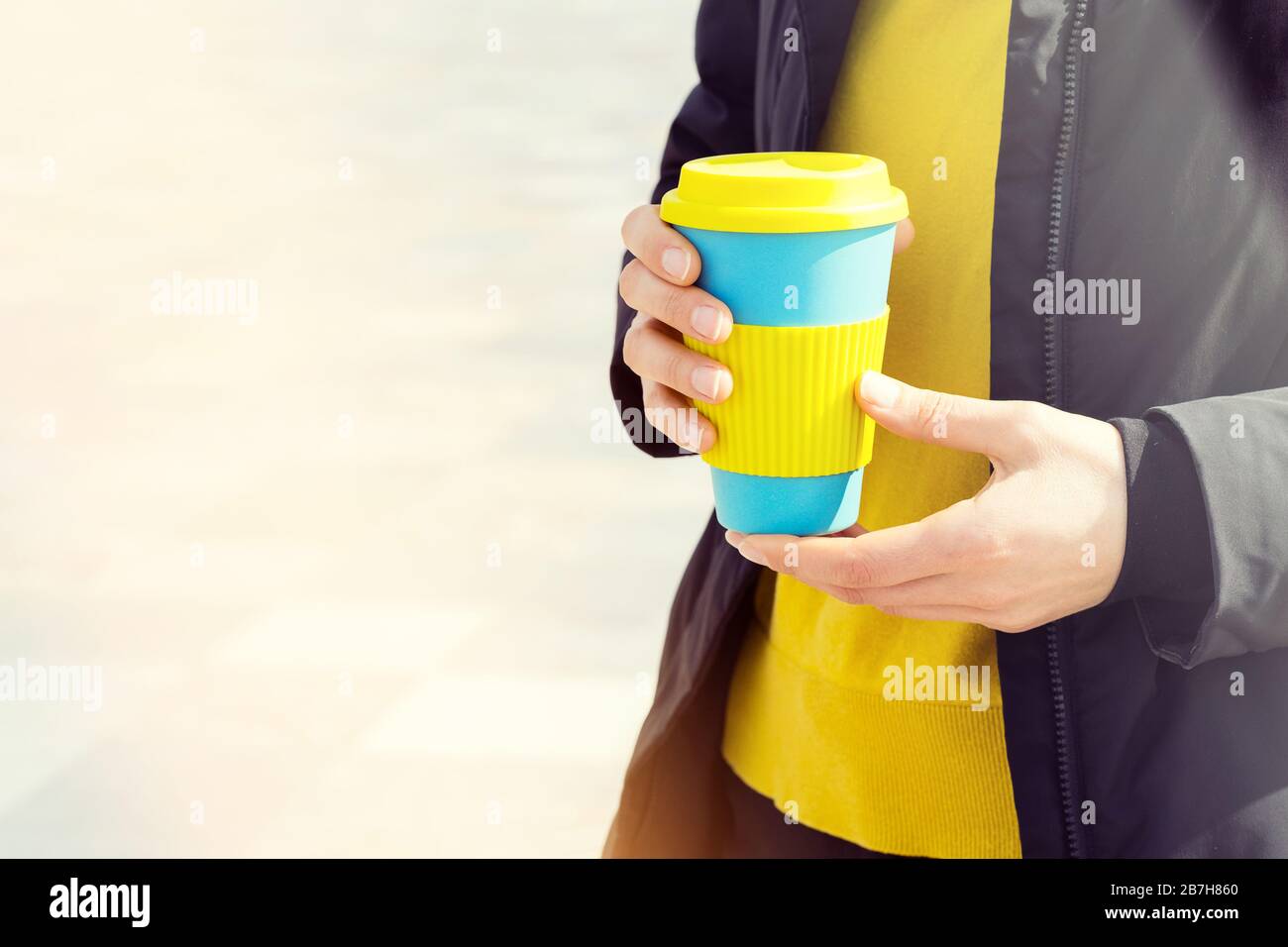 Taza de café reutilizable con las manos femeninas. Llévate el café a cualquier parte con una taza reutilizable. Foto de stock