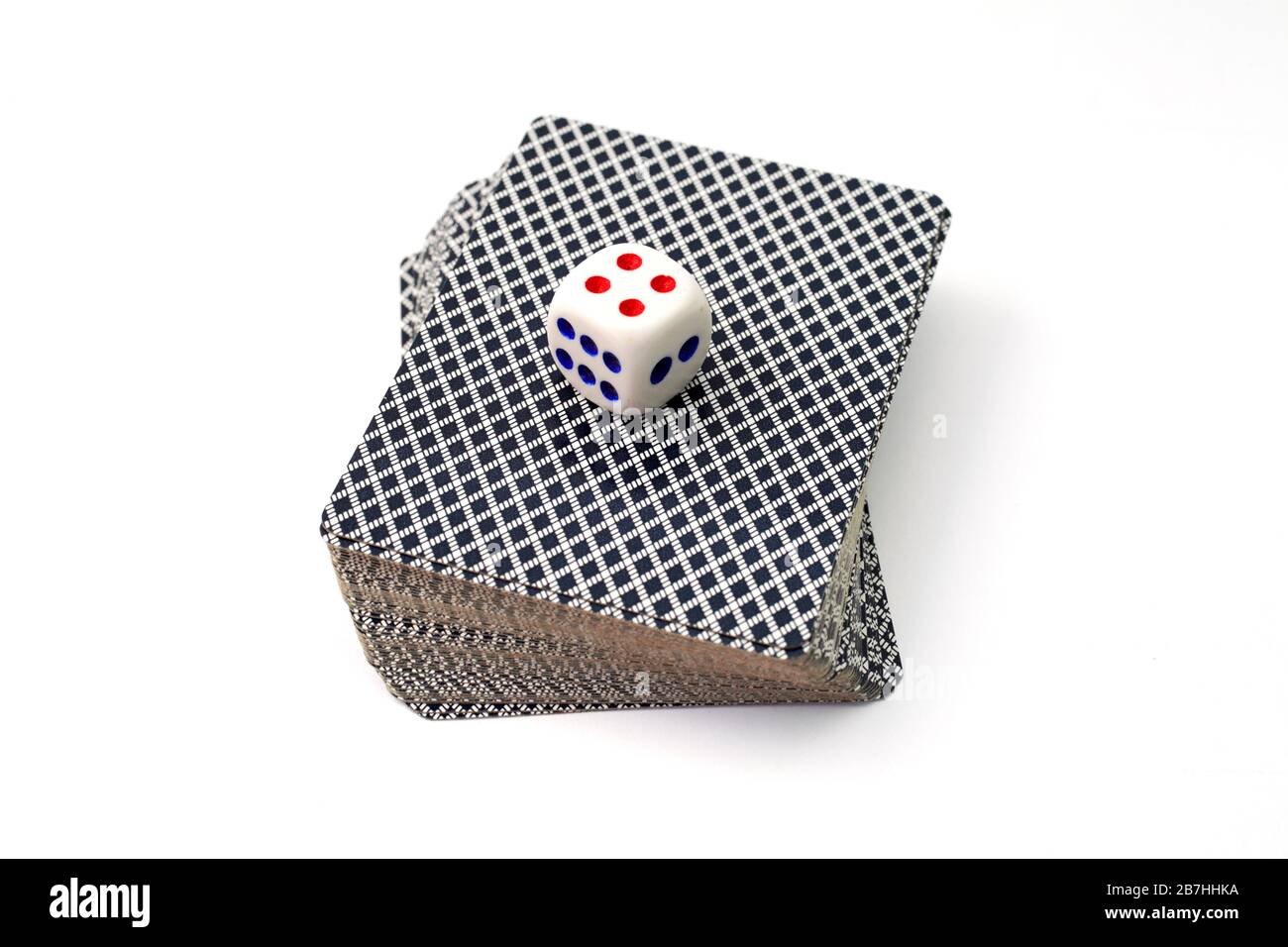 una baraja de cartas sobre un fondo blanco y un dado en la parte superior en un primer plano de la baraja Foto de stock