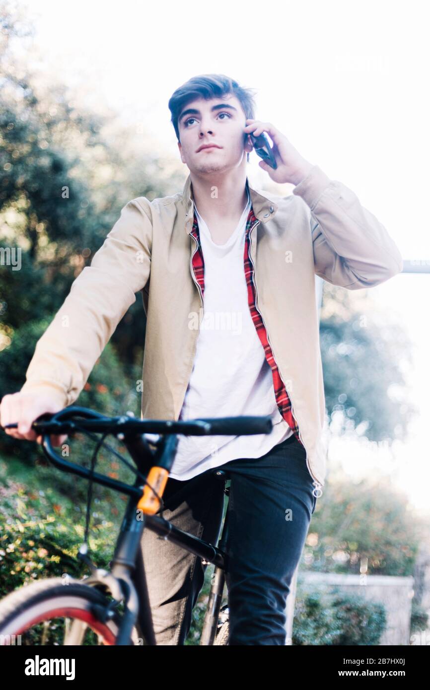 Hombre joven en bicicleta llamando por teléfono móvil Foto de stock