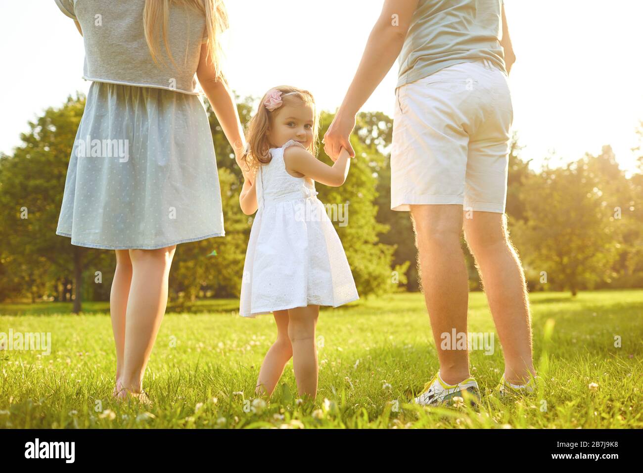 Feliz familia caminando en la hierba en el parque de verano. Día De La Protección De Los Niños. Foto de stock
