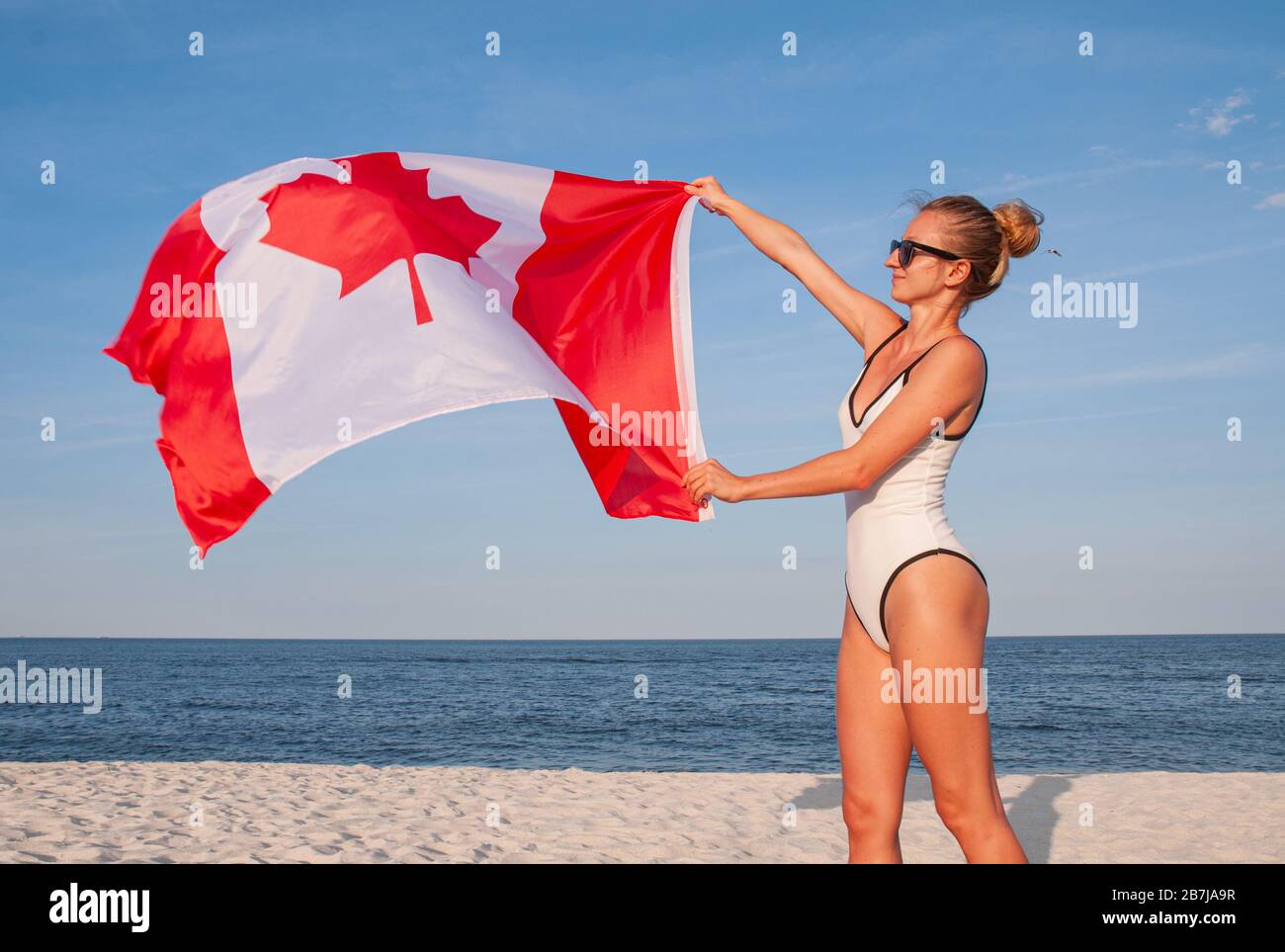 Bandera Nacional de Canadá. Hermosa mujer patriótica con bandera canadiense  en la playa Fotografía de stock - Alamy