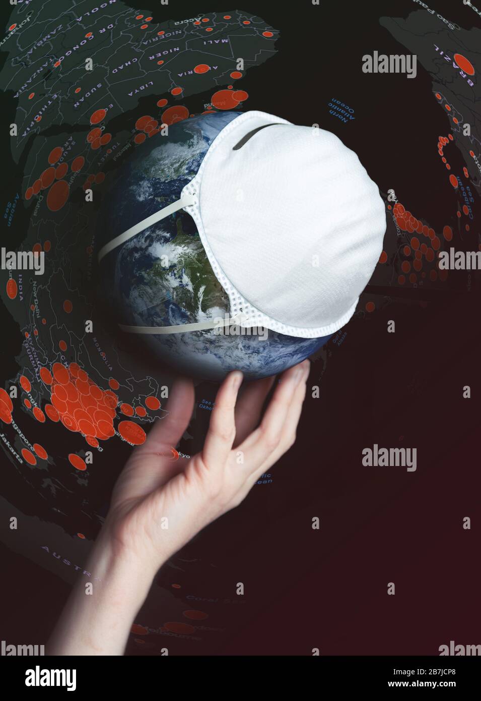 Una mano sostiene el globo con una máscara médica durante una epidemia de Covid 19 o coronavirus en todo el mundo. Concepto Foto de stock