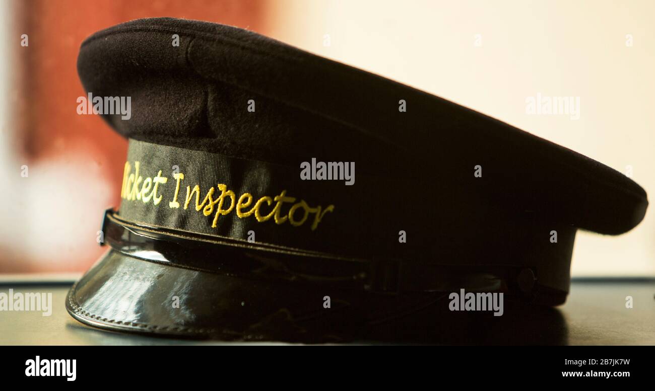 El primer plano de un inspector de billetes de ferrocarril histórico alcanzó la gorra negra con escritura de oro Foto de stock
