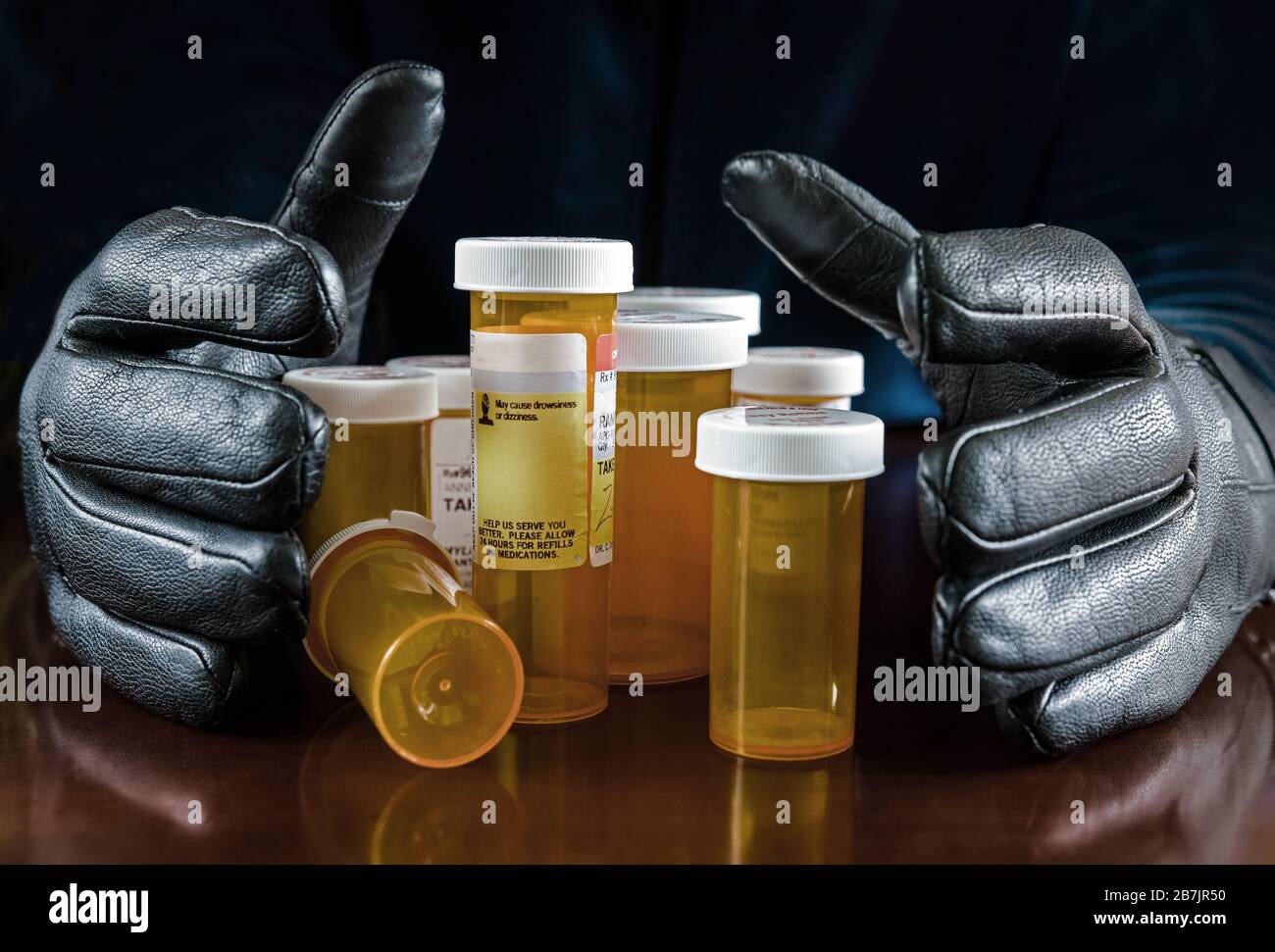 Dos manos enguantadas tratando de agarrar todos los envases de la medicina. Foto de stock