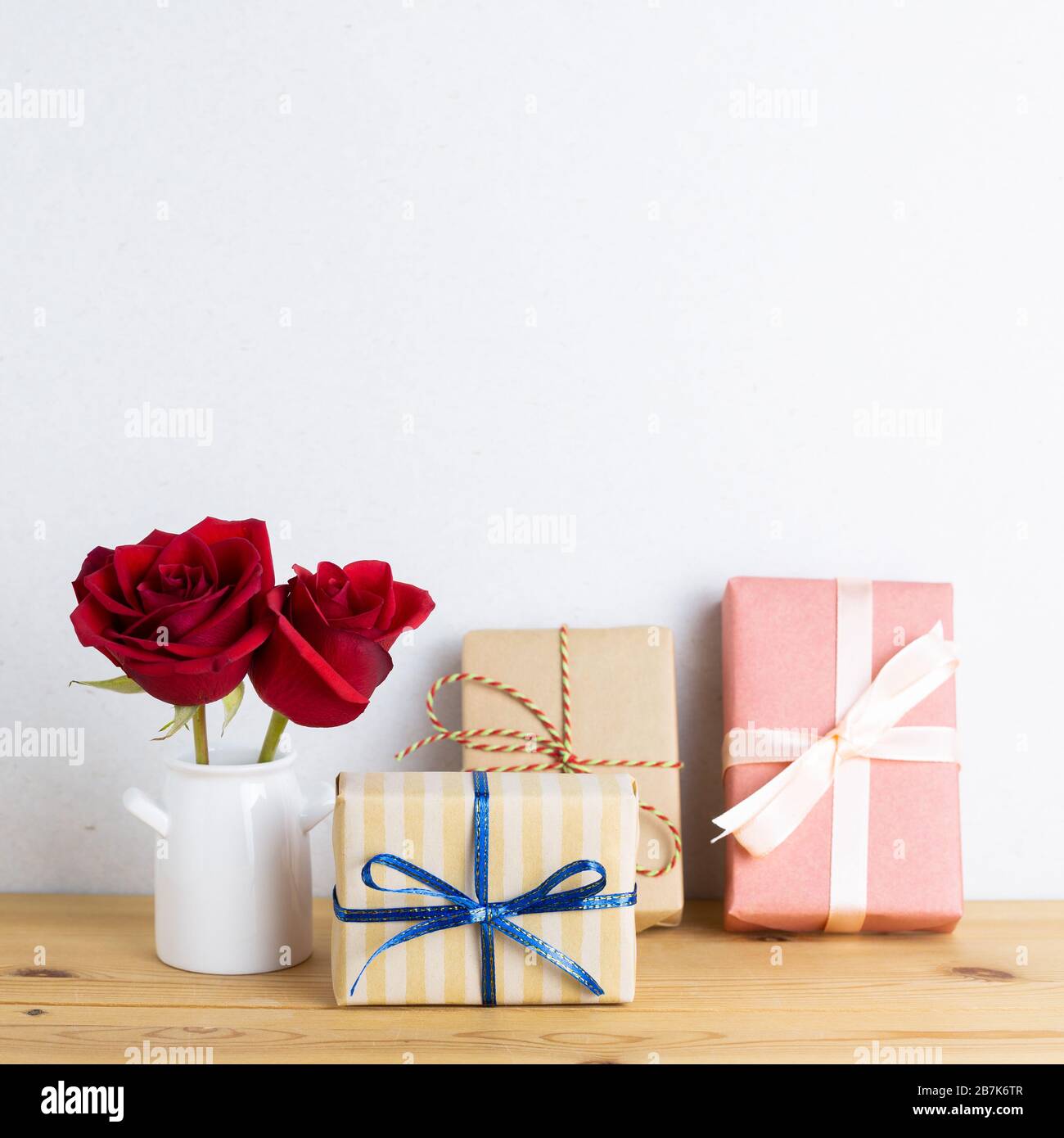 Cajas de regalo con flores de rosas rojas en jarrón sobre mesa de madera  con fondo blanco. Concepto de aniversario, arreglos florales, espacio para  copias Fotografía de stock - Alamy