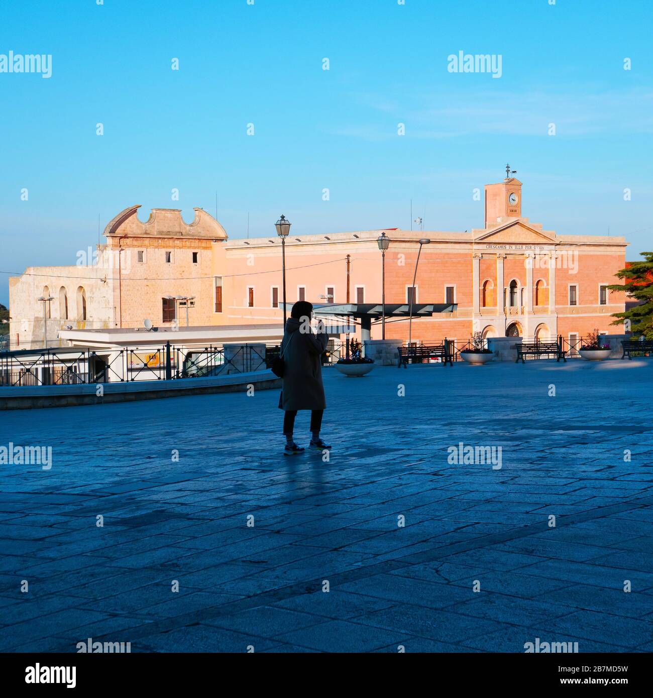 Conversano,Italia,02/24/2020: Mujer en el centro de la ciudad de Conversano en el invierno de la puesta de sol, a quien ella camina solo en la plaza. Foto de stock