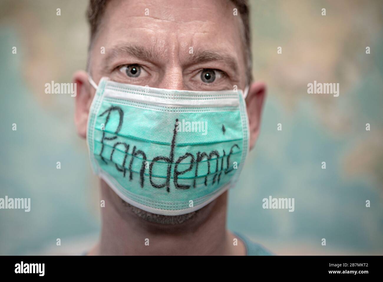Hombre caucásico con protector de la boca frente al mapa mundial, pandemia Foto de stock
