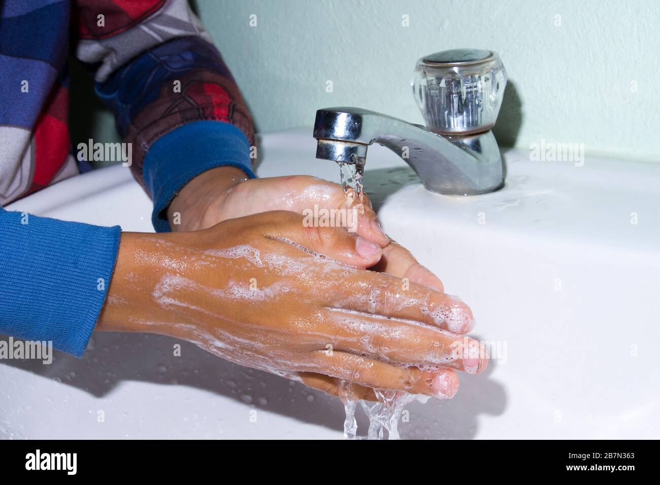 lavarse las manos del niño para prevenir bacterias en el fondo blanco Foto de stock