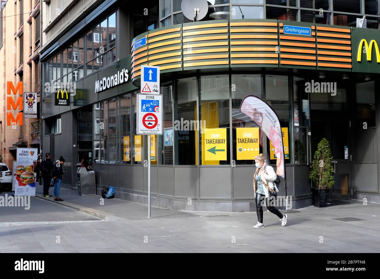 Una mujer que lleva una máscara camina en Basilea, todas las tiendas están cerradas exept supermercados y farmacias Foto de stock