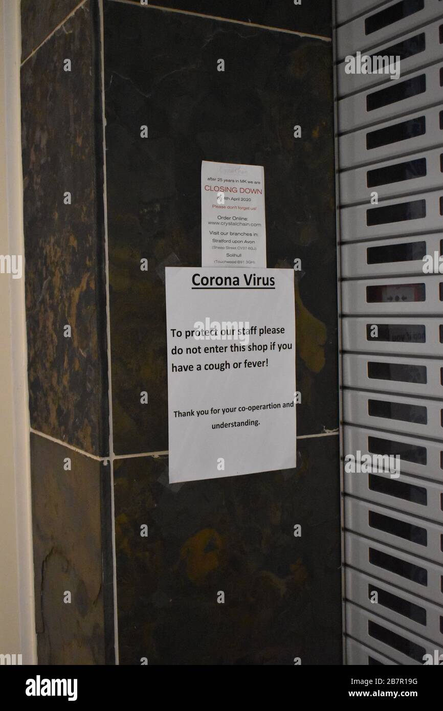 Un aviso en una tienda de Milton Keynes, pidiendo a la gente que se mantenga alejada si tienen síntomas de coronavirus. Foto de stock