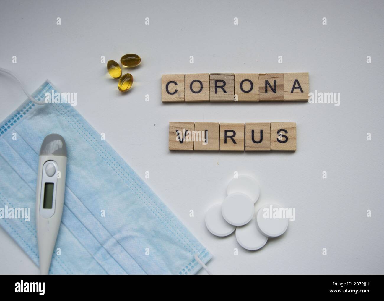 Azulejos cuadrados de madera con las letras DEL VIRUS CORONA, aislados sobre fondo blanco, covid-10 pandemia, virus de la corona, termómetro, máscara y tabletas y pil Foto de stock
