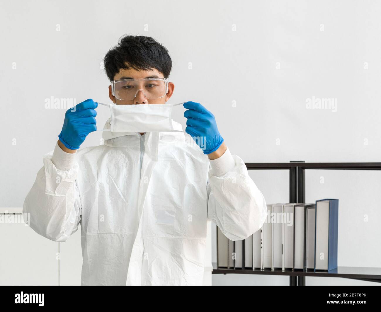 Científicos asiáticos inspeccionan la calidad de una máscara antes de comenzar el experimento en un laboratorio científico. Foto de stock