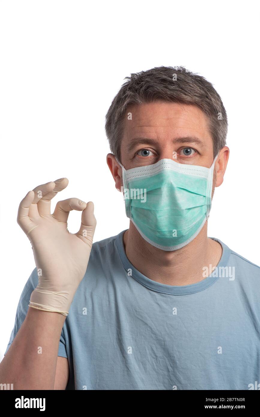 Hombre caucásico con una máscara de protección y haciendo vistory signo con guantes de protección sobre un fondo blanco Foto de stock