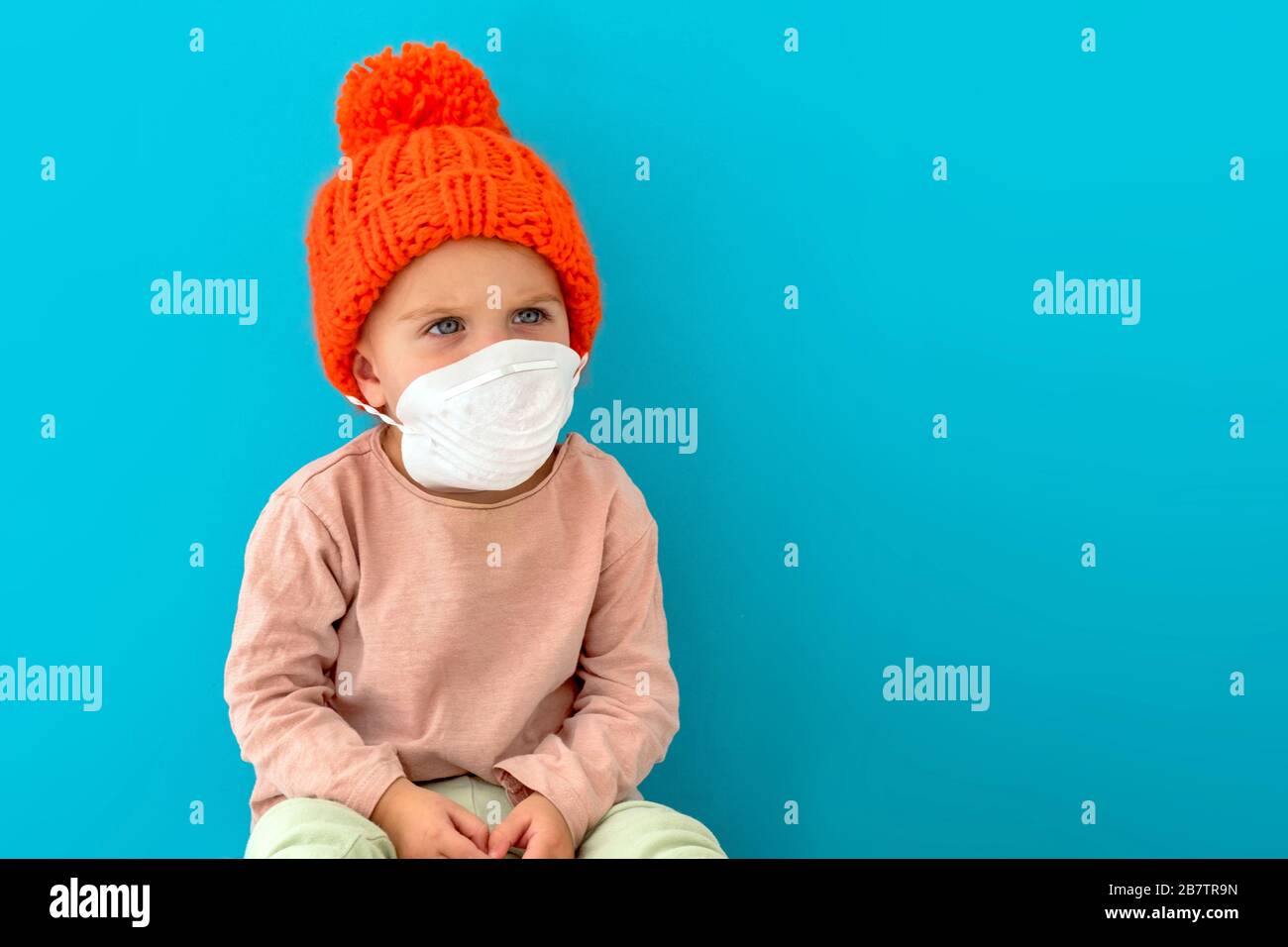 Niño en una máscara médica sobre fondo azul Foto de stock