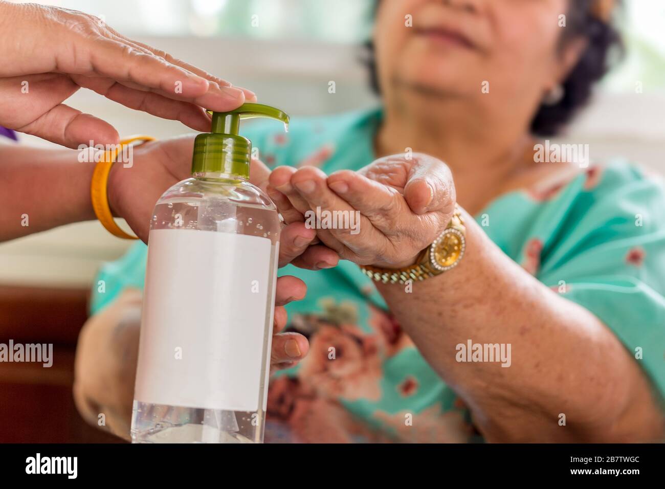 Mujer mayor aplicando gel de alcohol en la mano para prevenir gérmenes, coronavirus. Foto de stock