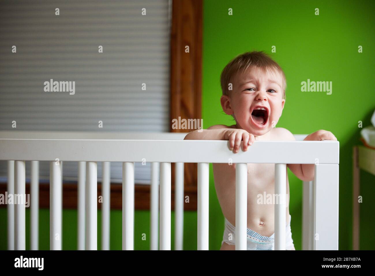 Baby Boy de pie en Crib gritos Foto de stock