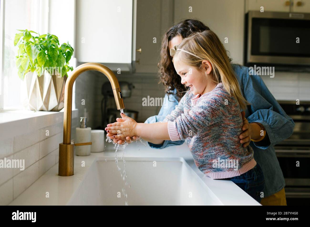 Madre e hija, en el lavado de manos en el lavabo de la cocina Foto de stock