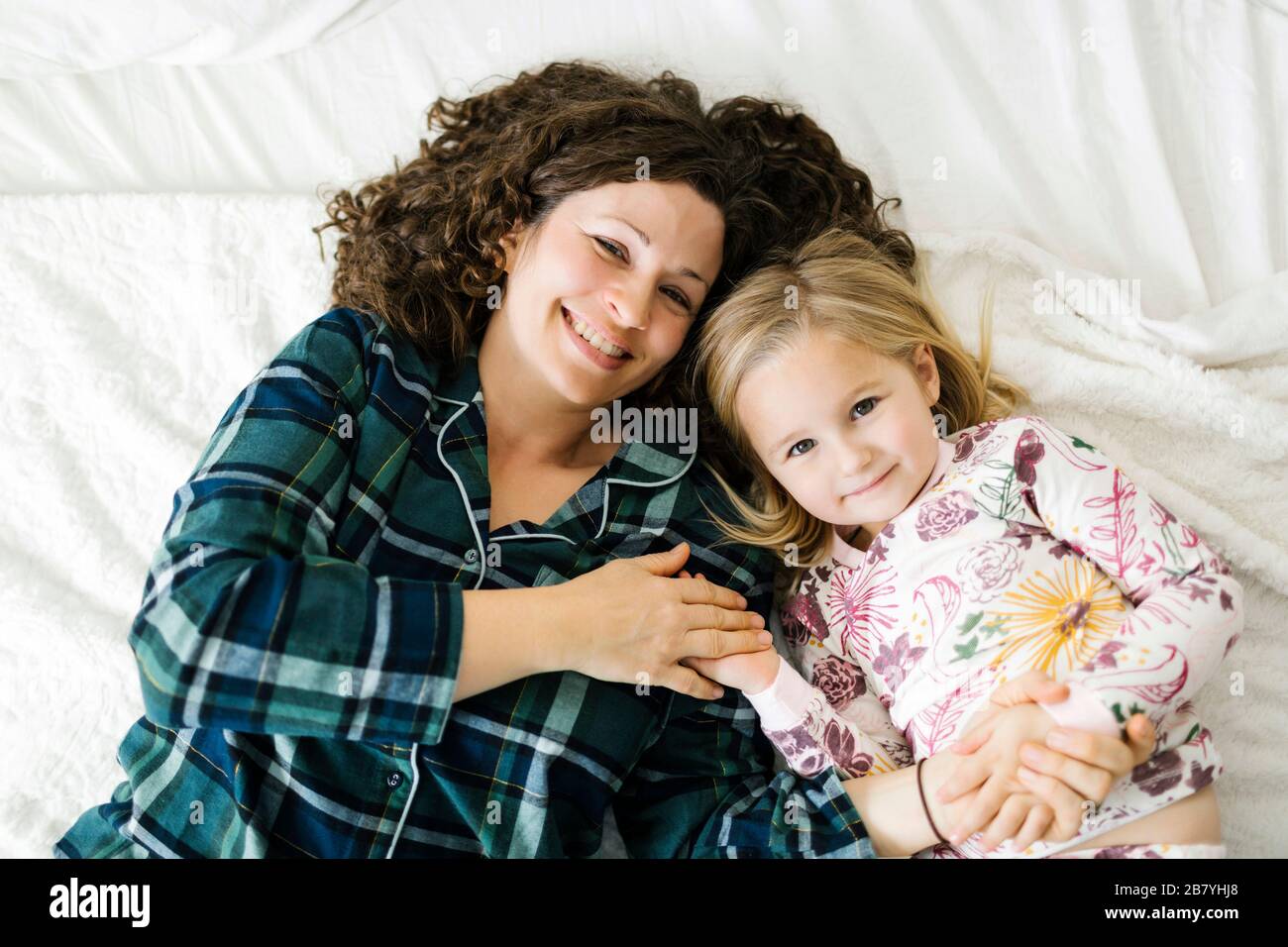 Vista en ángulo alto de la madre y la hija en pijamas acostados en la cama Foto de stock