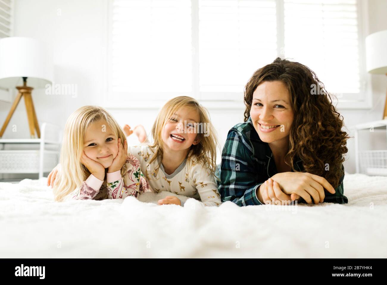 Madre e hijas acostadas en la cama en pijamas Foto de stock