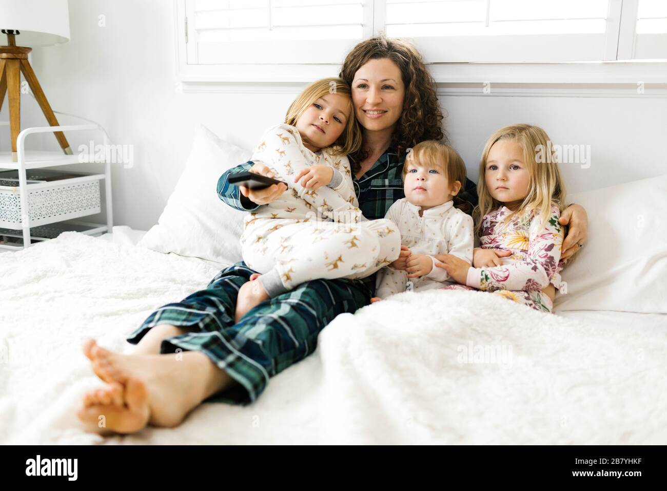 Mujer sentada con sus hijas en la cama Foto de stock