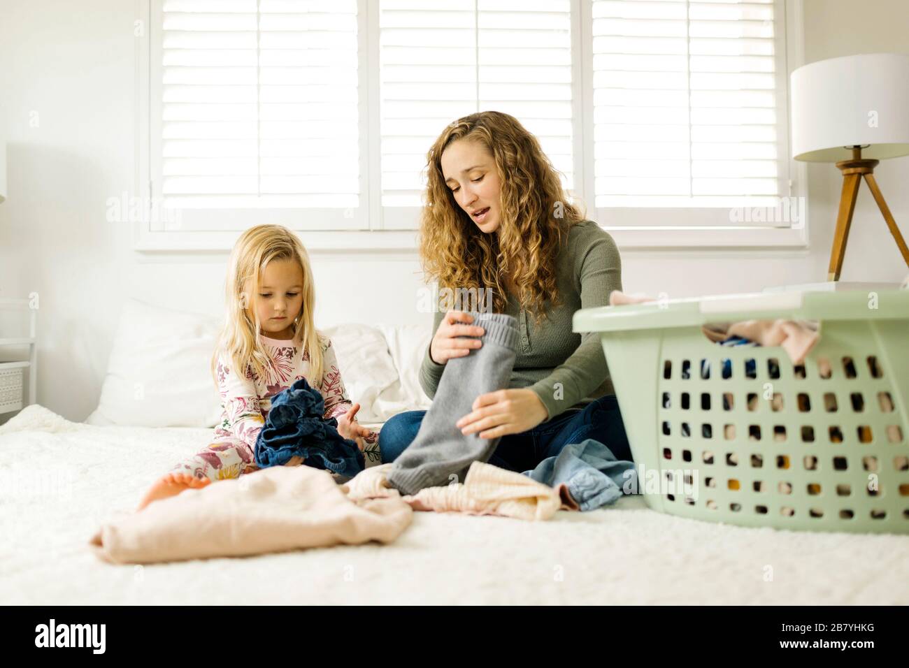 La madre y la hija doblan la ropa en la cama Foto de stock