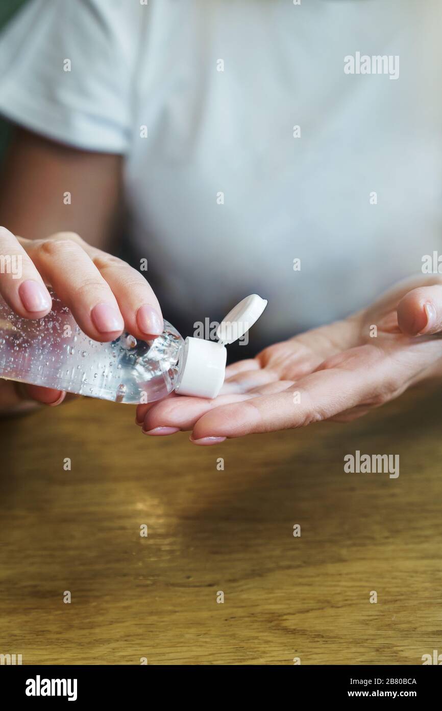 Una mujer en un café le trata las manos con un desinfectante antiséptico Foto de stock