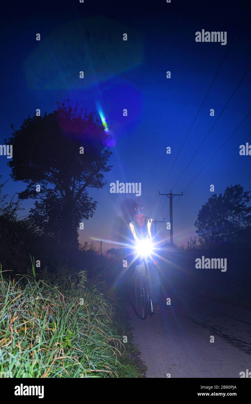 ciclista montando a lo largo de la carretera del país en el crepúsculo york yorkshire reino unido Foto de stock