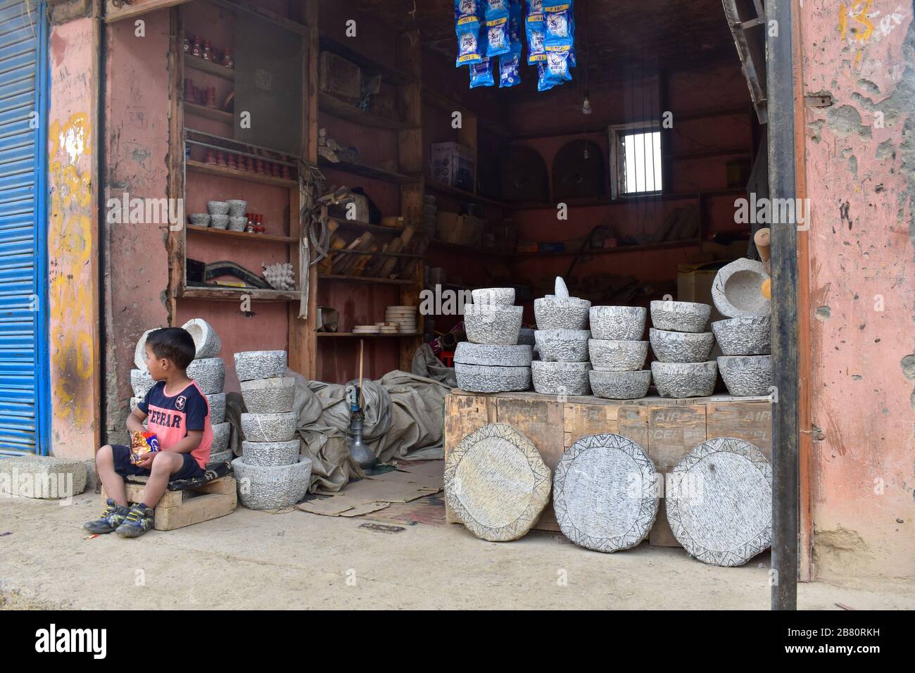 Un niño sentado en un taller de piedra en Cachemira bajo encierro. Foto de stock