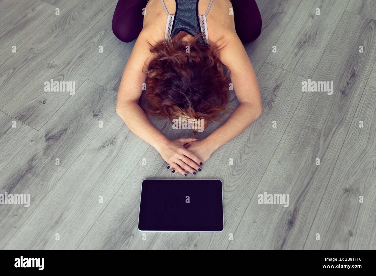 vista en ángulo alto de una mujer joven sola después de una clase de yoga en casa utilizando una tableta Foto de stock