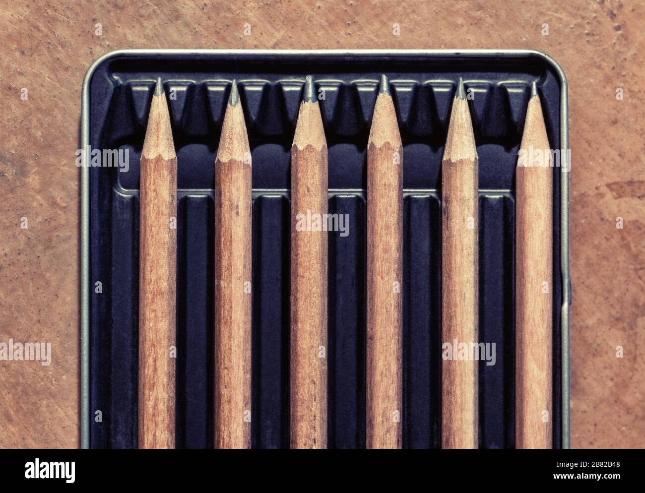 Lápices de madera en una caja, separados por un espacio vacío. Imagen conceptual para distanciamiento social. Foto de stock