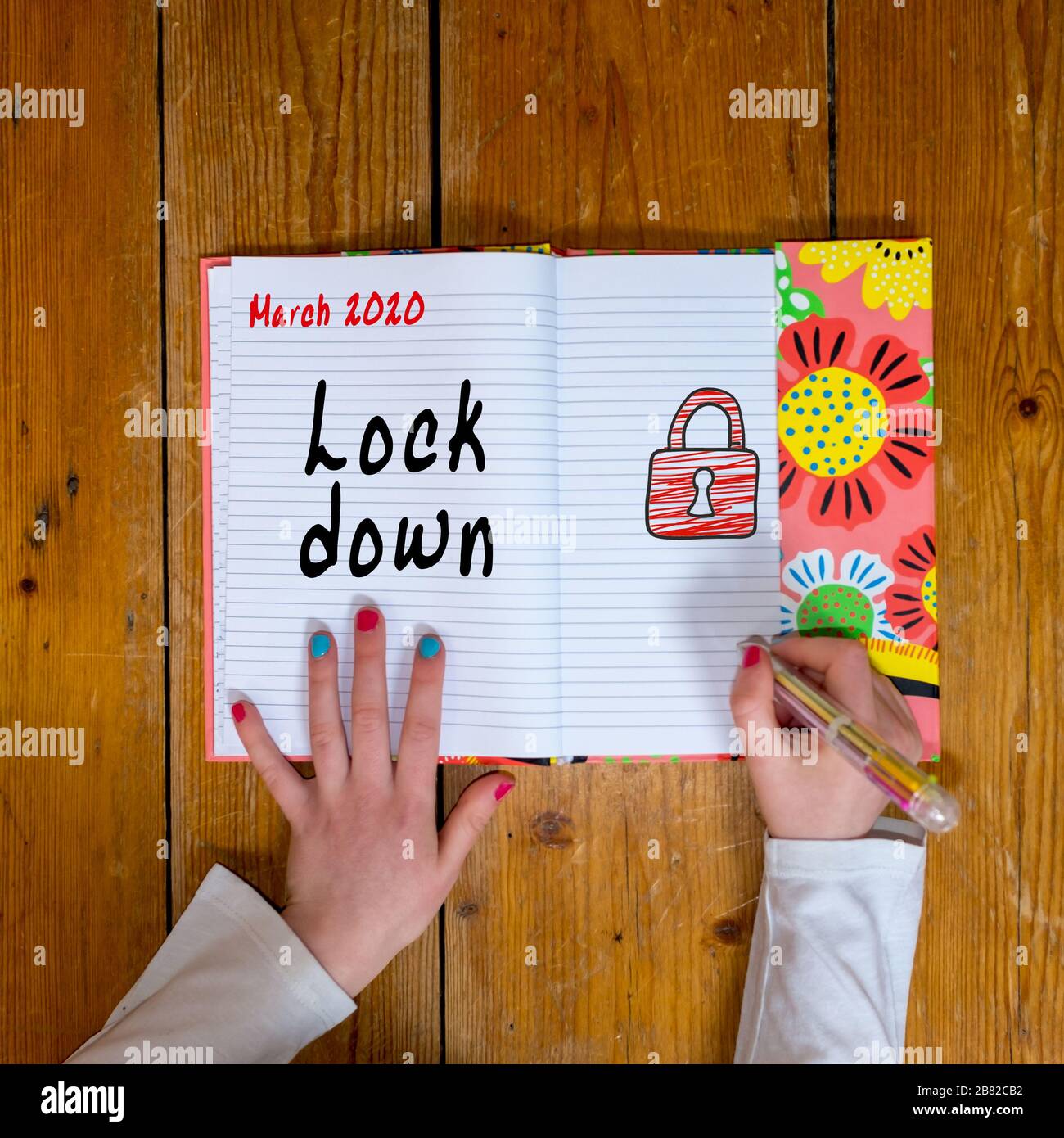 Chica escribiendo bloqueo en su diario para marzo de 2020 Foto de stock