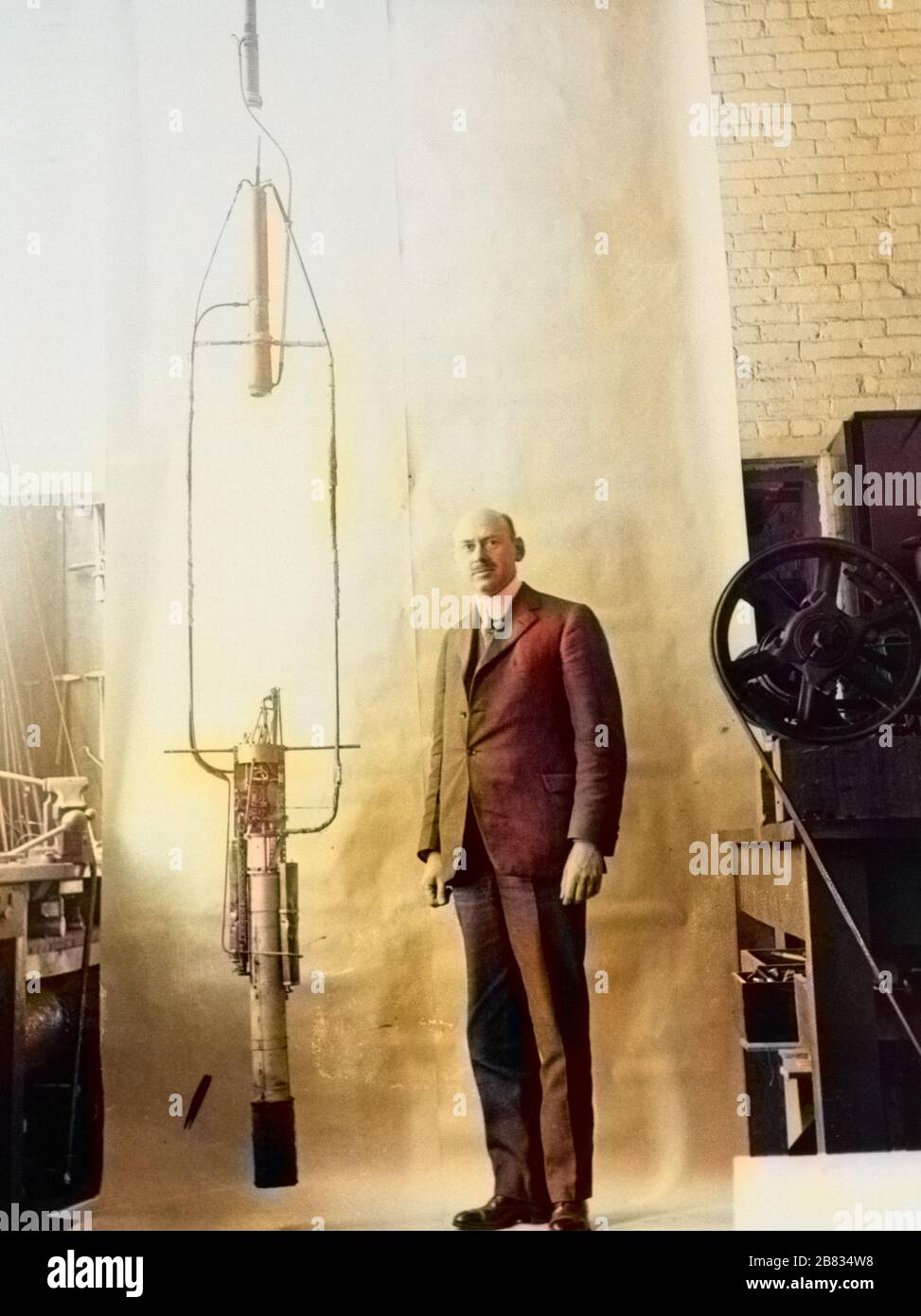 Dr. Robert H. Goddard posando junto a su cohete de combustible líquido, 1882. Imagen cortesía de la Administración Nacional de Aeronáutica y del espacio (NASA). Nota: La imagen se ha coloreado digitalmente mediante un proceso moderno. Es posible que los colores no tengan precisión de punto. () Foto de stock