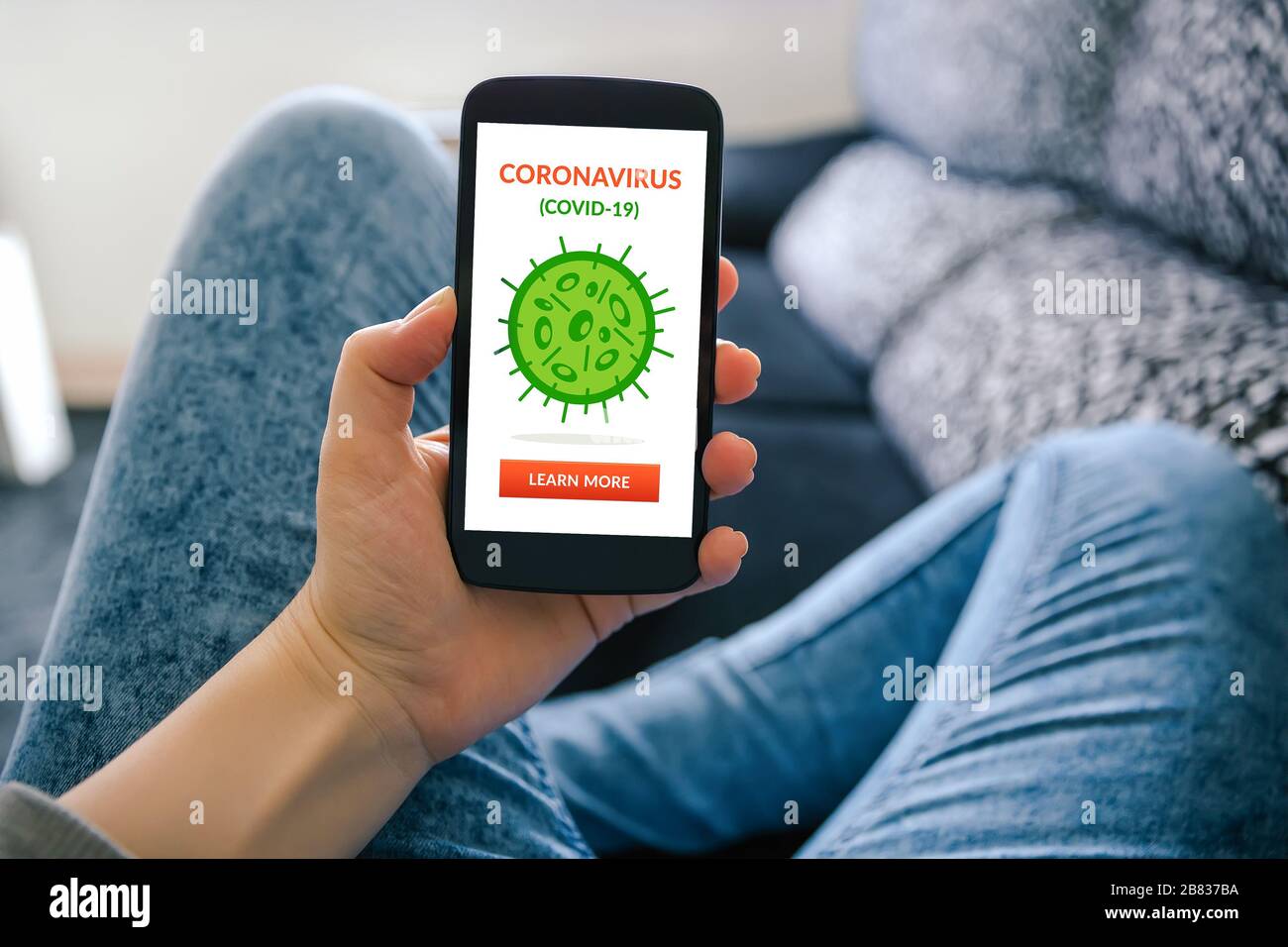 Niña sosteniendo un teléfono inteligente con coronavirus, concepto covid-19 en la pantalla. Distanciamiento social Foto de stock