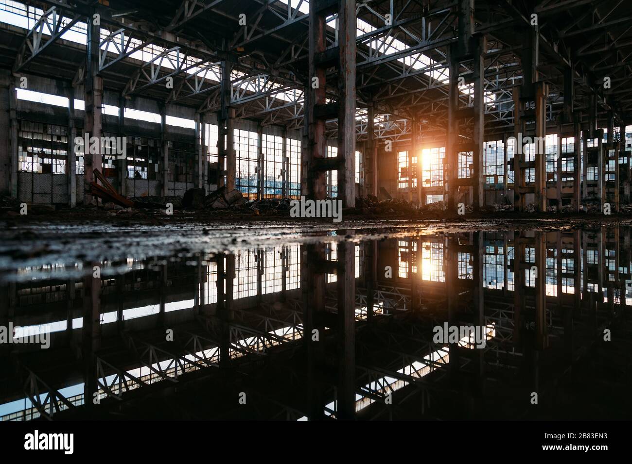 Dentro de un sucio inundado abandonado edificio industrial arruinado con reflexión de agua Foto de stock