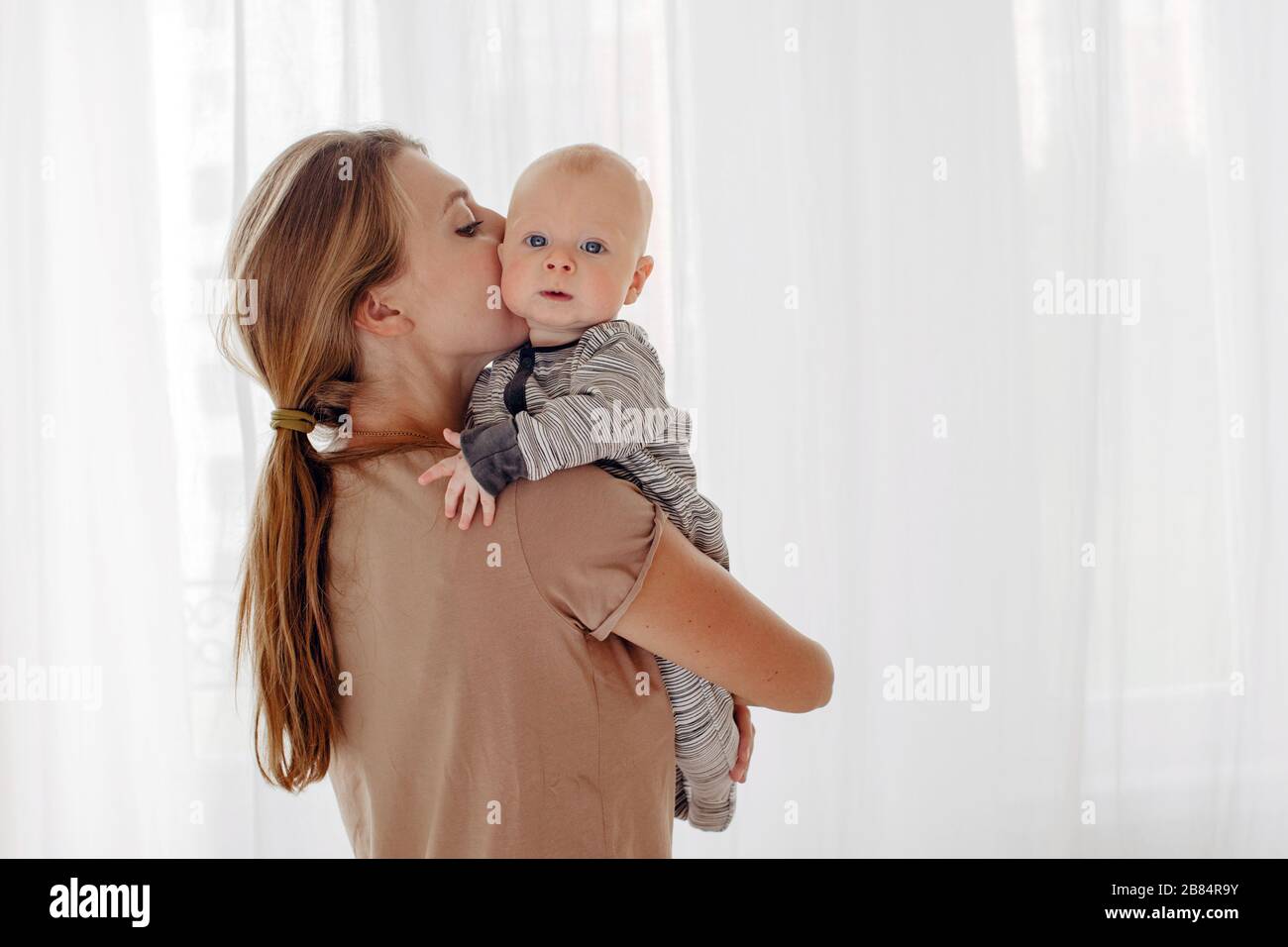 Madre besos y abrazos de bebé Foto de stock