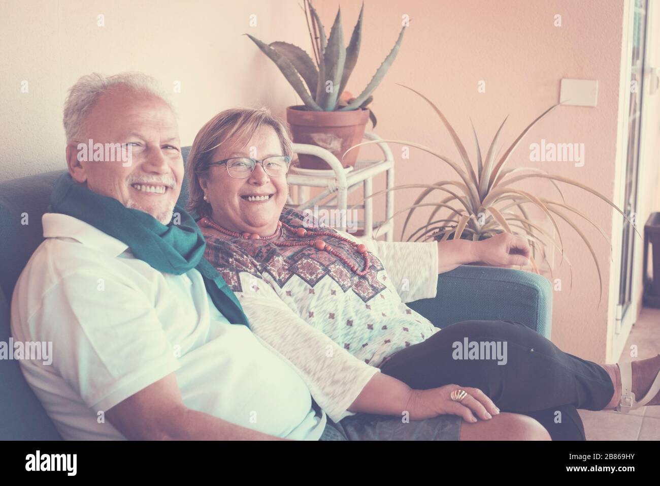 Alegre pareja feliz de edad avanzada sentarse en el sofá en casa juntos sonriendo y mirando bien la cámara para una familia de retratos - rel Foto de stock