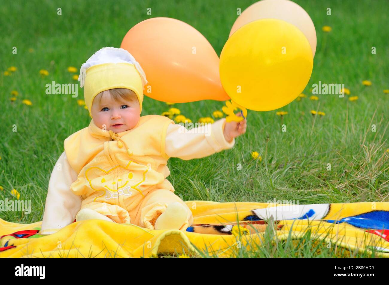 Funeral contrabando basura Foto de lindo bebé con ropa amarilla para niños sentado en el césped con  dientes y sosteniendo globos en la mano Fotografía de stock - Alamy