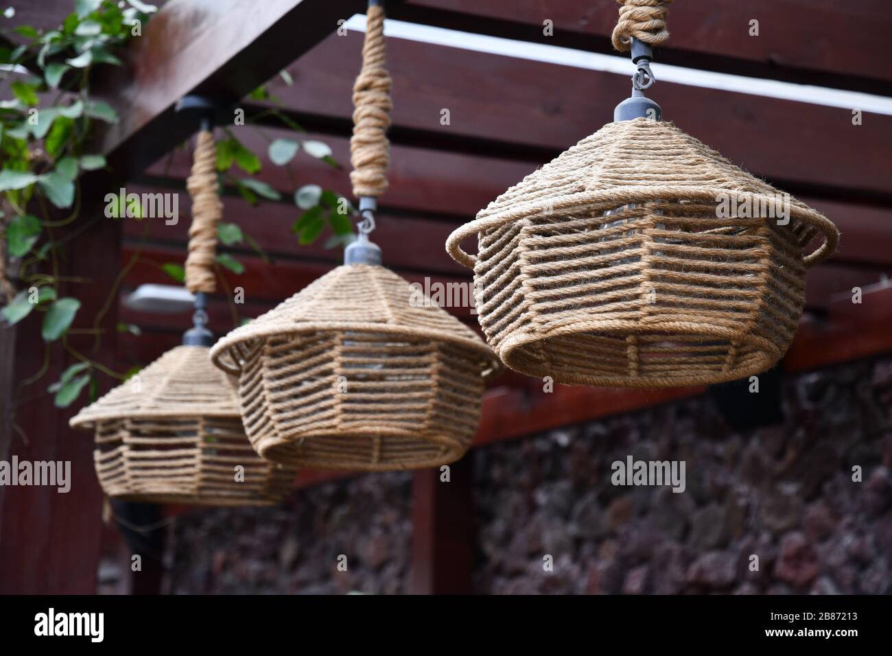 Primer plano de las luces colgantes tejidas tradicionales chinas que cuelgan de la azotea de madera. Lámparas de hilo de mimbre fabricadas a mano en un estilo ecológico. Decoración asiática Foto de stock