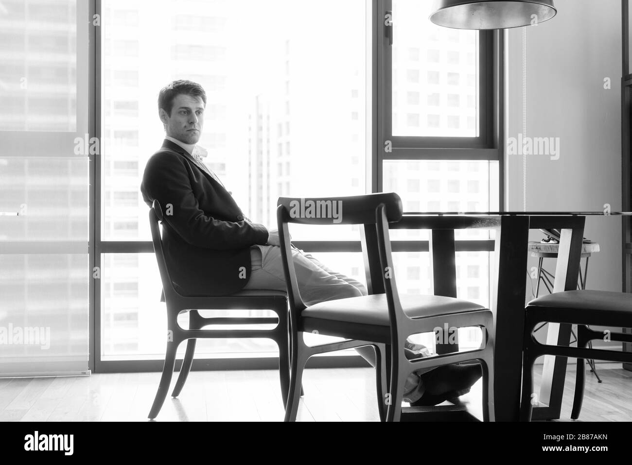Joven hombre de negocios guapo sentado en el comedor cerca de la cocina Foto de stock