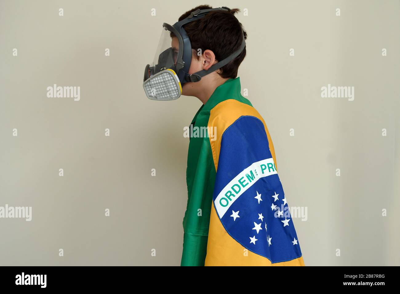Río de Janeiro, Brasil, 20 de marzo de 2020. Niño con máscara de protección facial contra gases y olores envueltos en la bandera brasileña. Foto de stock