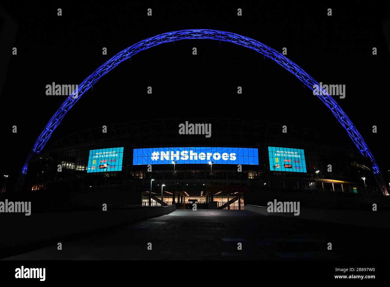 El Arco de Wembley está iluminado en azul para mostrar su apreciación al NHS en medio del brote de coronavirus en Londres, Después de que el primer Ministro Boris Johnson ordenara que los pubs y restaurantes de todo el país cerraran esta noche, cuando el Gobierno anunció medidas sin precedentes para cubrir los salarios de los trabajadores que de otra manera perderían sus empleos debido al brote de coronavirus. Foto de stock