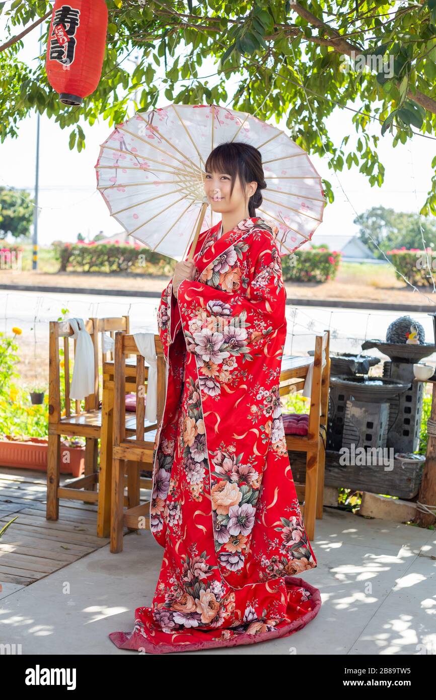 La niña lleva un kimono rojo tradicional, que es el vestido nacional de  Japón y sostiene un paraguas Fotografía de stock - Alamy