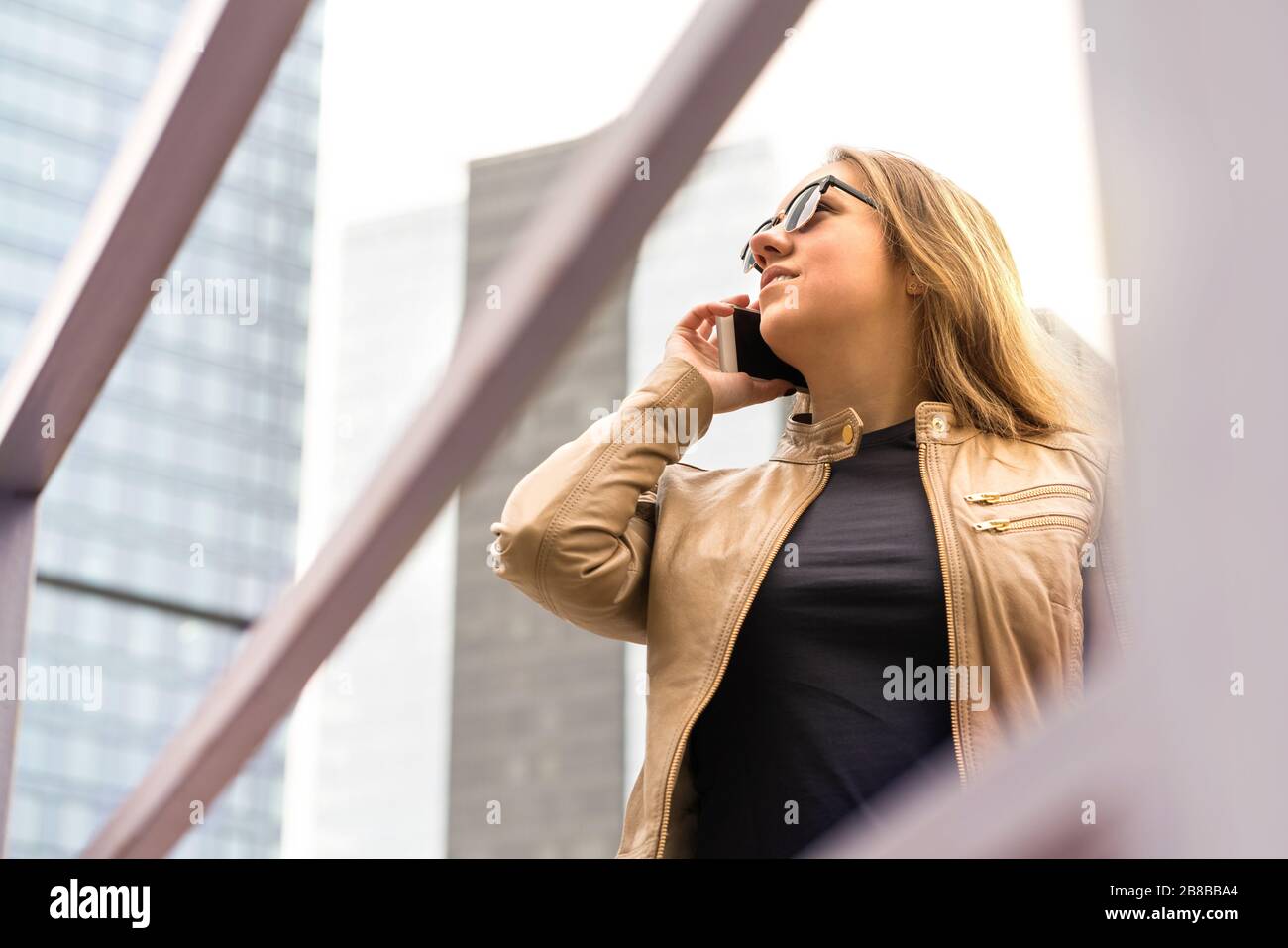 Mujer hablando por teléfono en la ciudad. Llamada de dama con smartphone. Cara neutra o grave. Foto de stock
