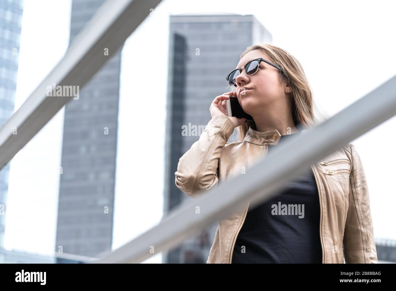 Mujer frustrada hablando por teléfono en la ciudad. Señora molesta o seria con el smartphone tensionando. Foto de stock