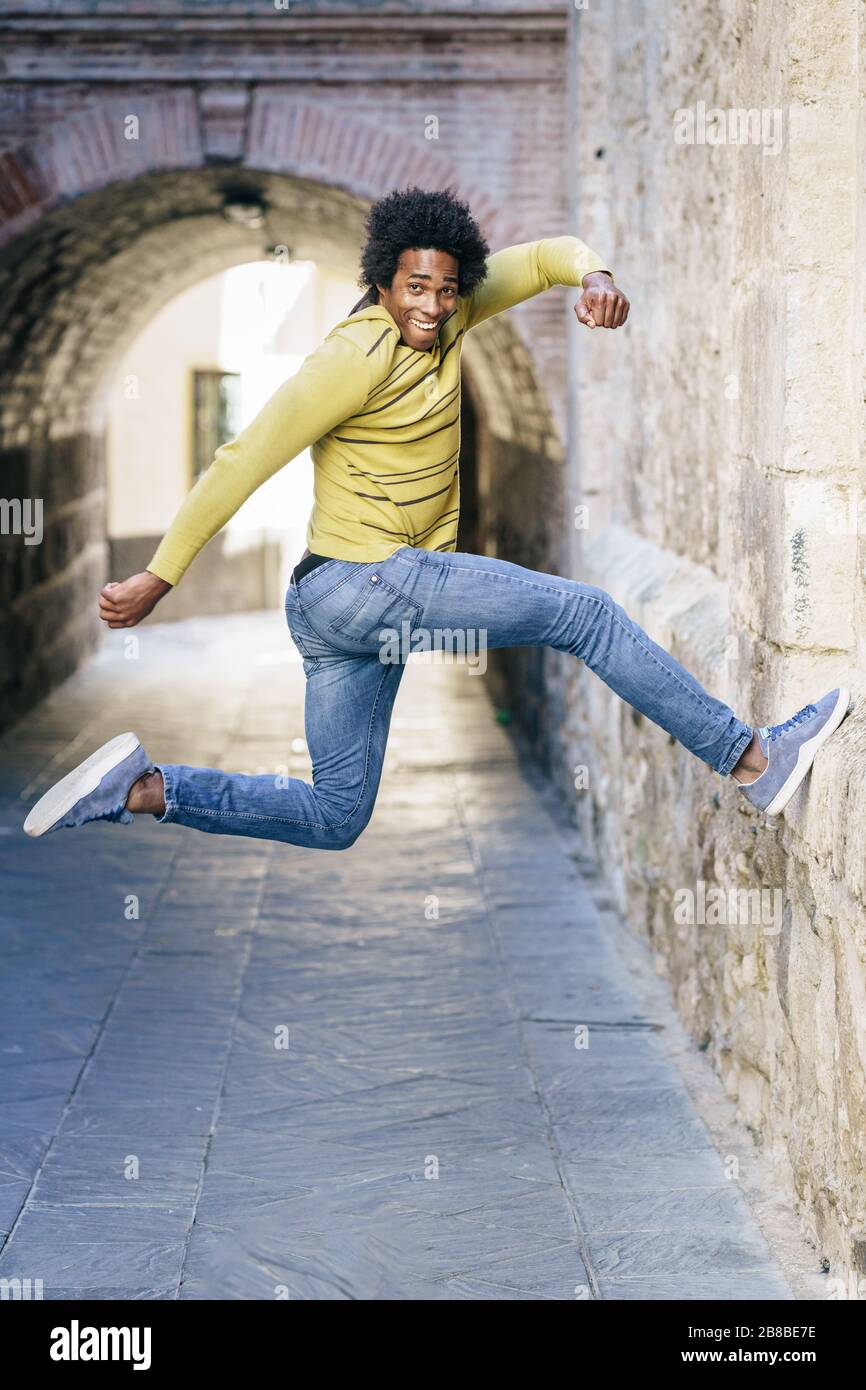 Hombre negro con el pelo afro saltar para la alegría Foto de stock