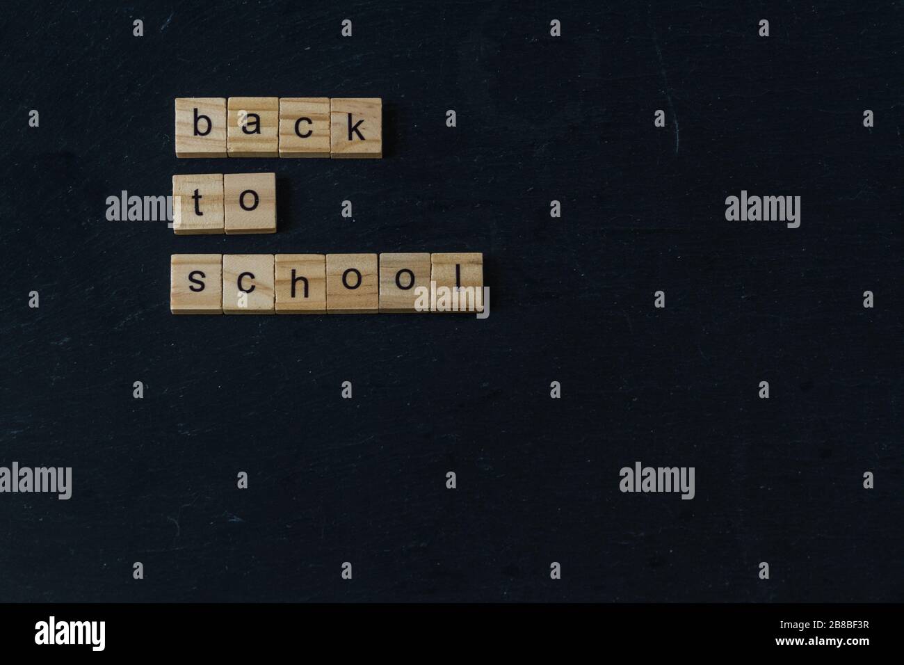 Volver a la Escuela escrito en bloques de madera de letras sobre fondo oscuro pizarra. CopySpace a continuación. Foto de stock