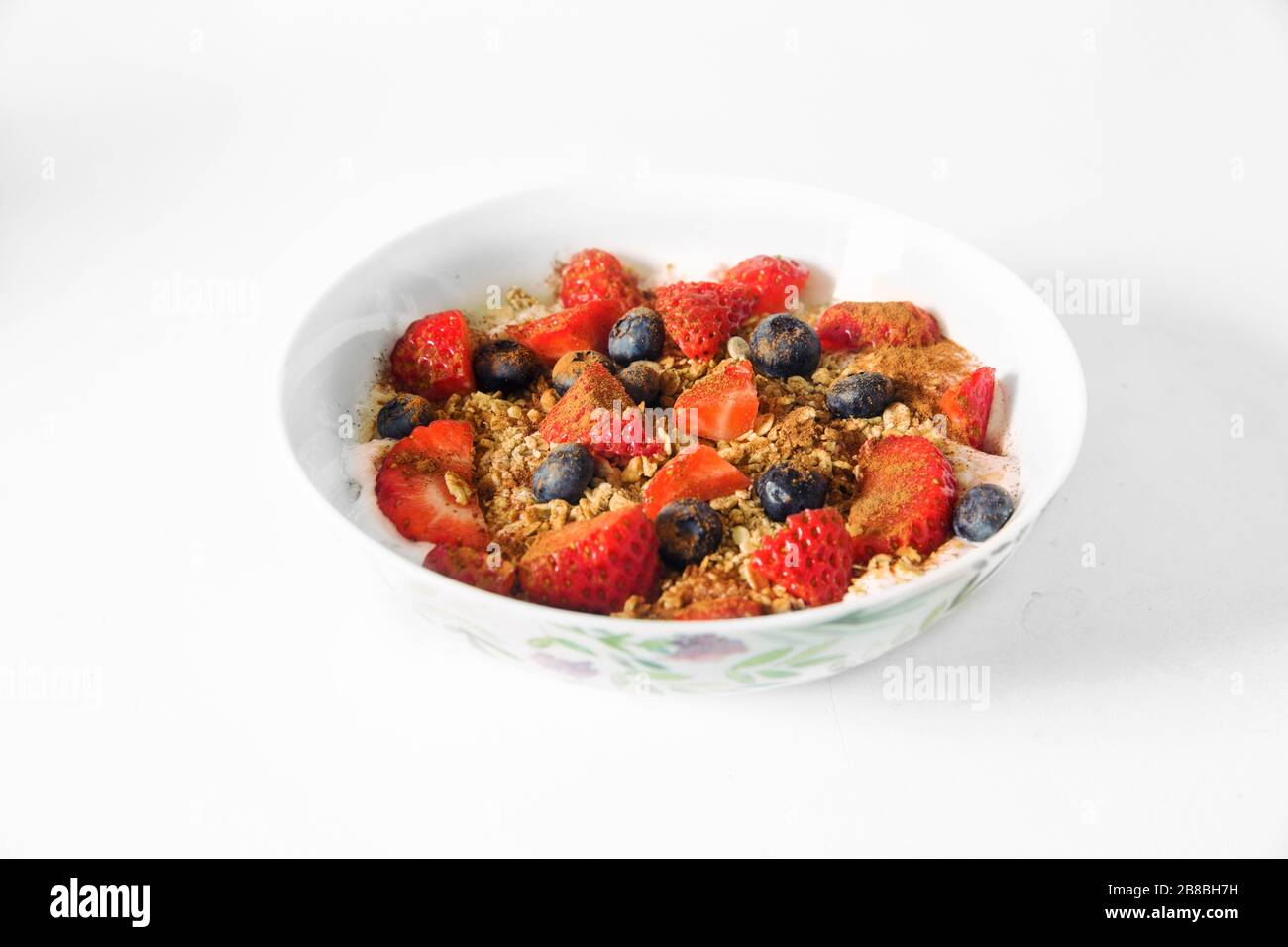 Un saludable Desayuno Feliz de Oatmeal para un tiempo de aislamiento. Un cuenco de avena, granola, fresa, arándanos, yogur, con cuenco blanco, fondo blanco Foto de stock