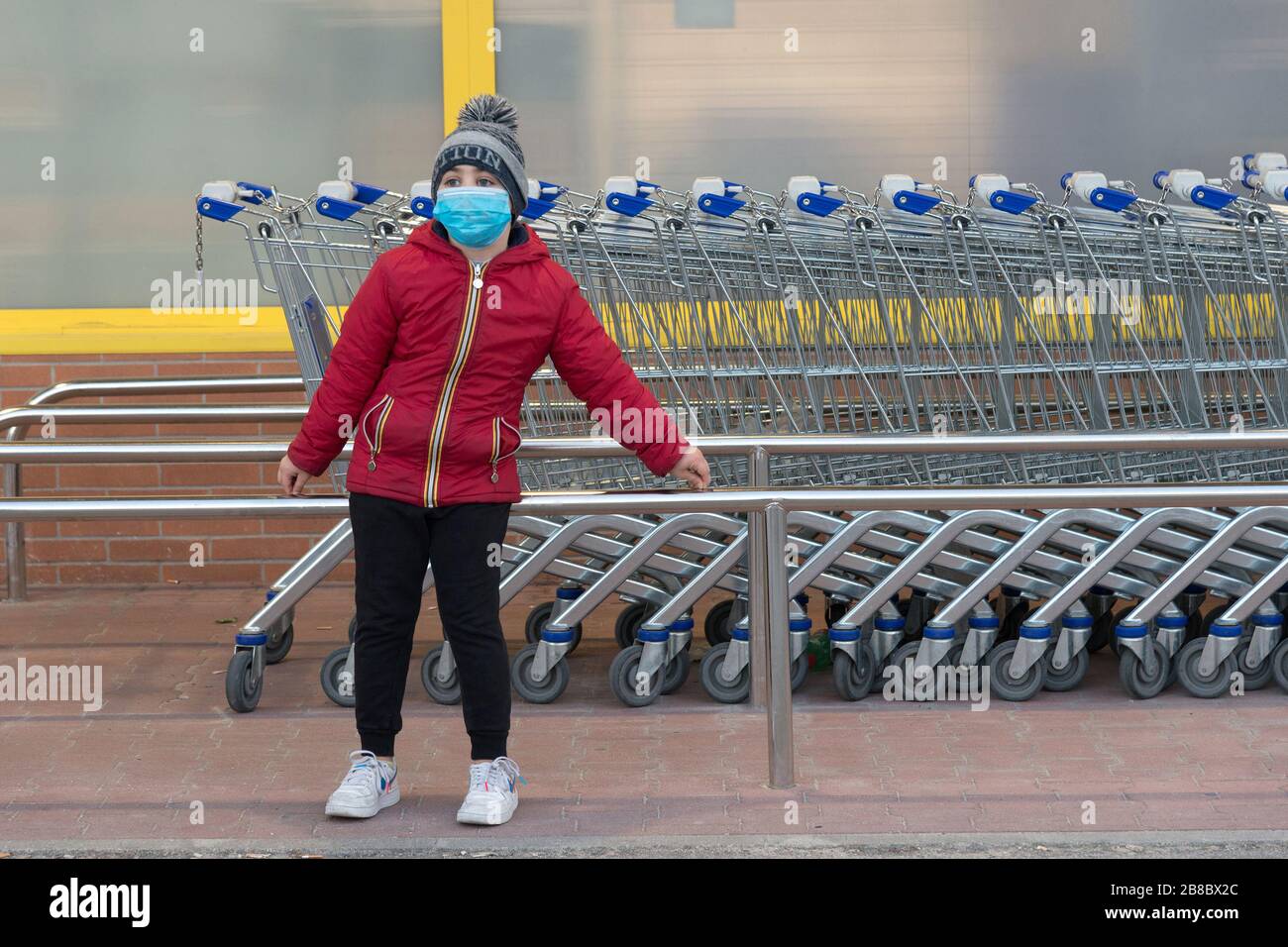 Campobasso,Molise Region,Italia:UNA niña espera a los padres cerca de los carritos de compras en frente de un supermercado durante la emergencia del coronavirus en C. Foto de stock