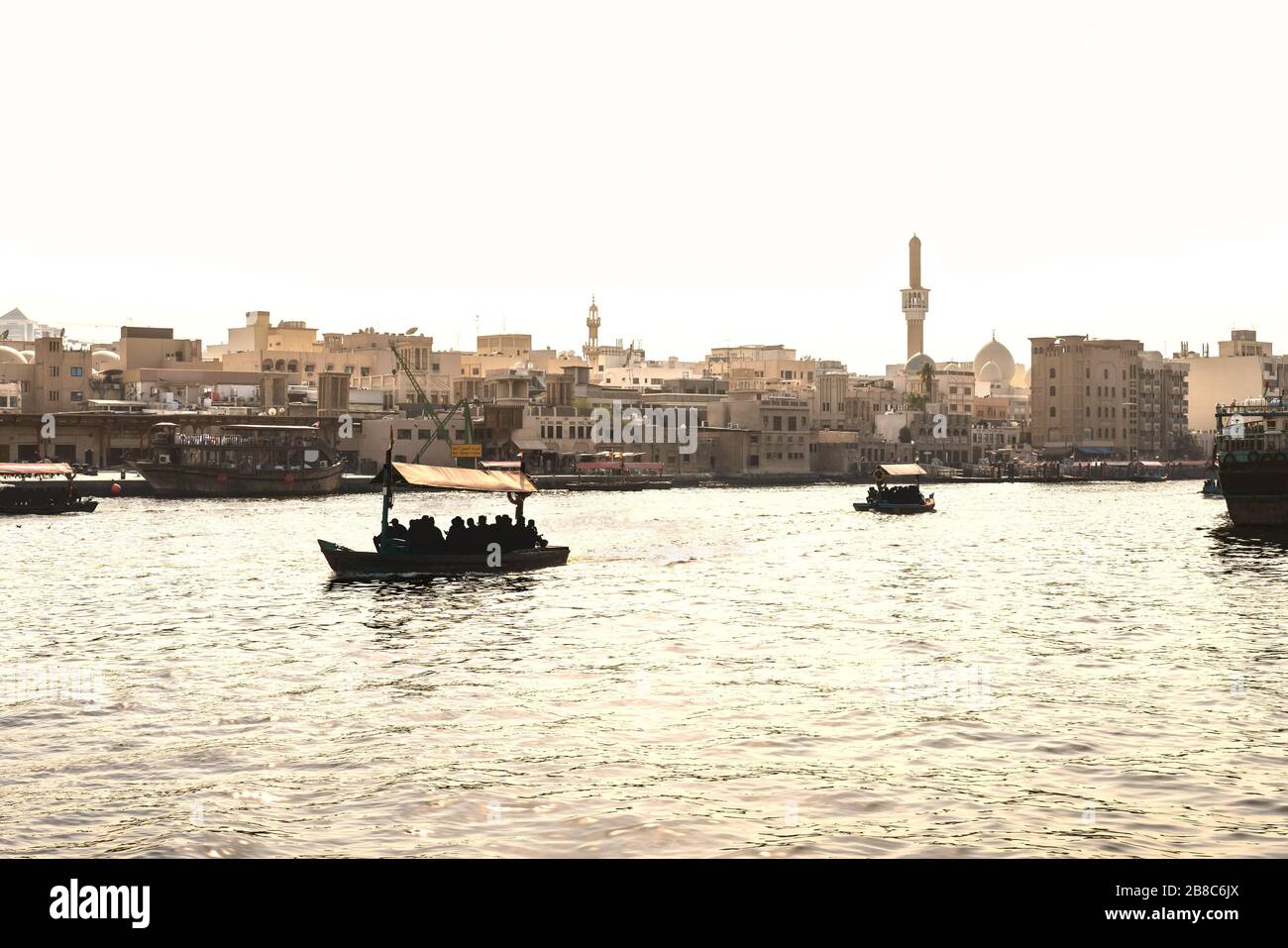 Dubai Creek con barcos abra. Gente local y turistas utilizando taxi acuático y ferry en el río de la ciudad vieja. Crucero tradicional. Vista panorámica de la ciudad árabe. Foto de stock