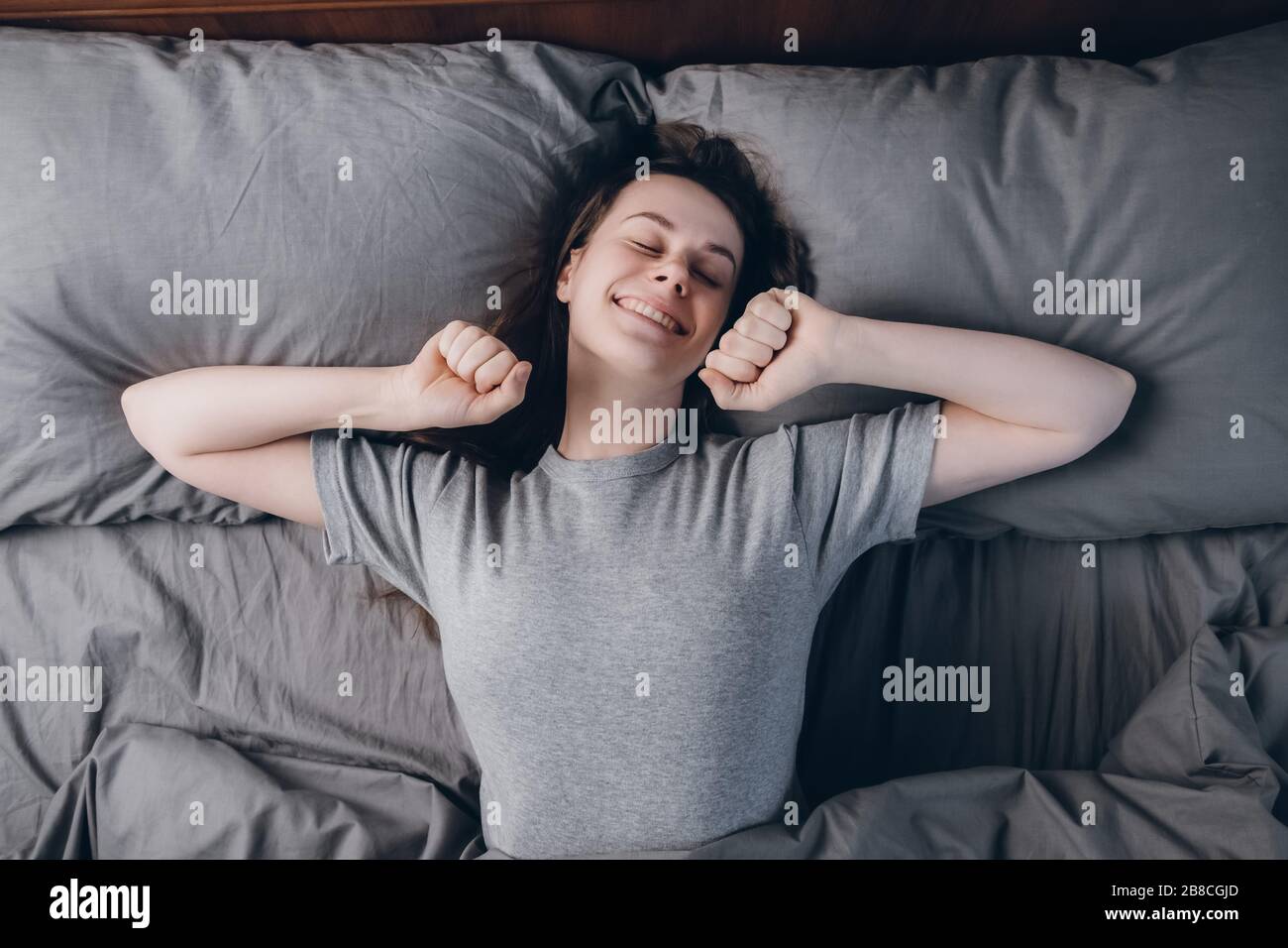 Vista superior de feliz mujer se estira las manos, se ríe feliz como ve  sueños agradables, mantiene los ojos cerrados, vestido con ropa informal  Fotografía de stock - Alamy